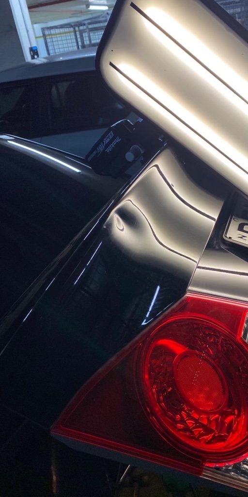 Red tail-light panel dent (before repair)